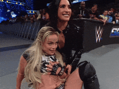 two women are posing for a picture in front of a wrestling ring with the letter w on it