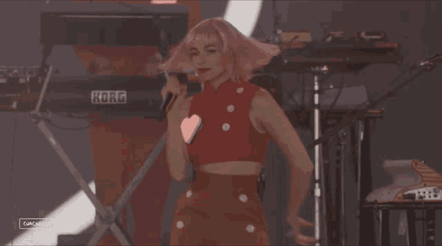 a woman in a red top is dancing in front of a keyboard with the word coachella on the bottom