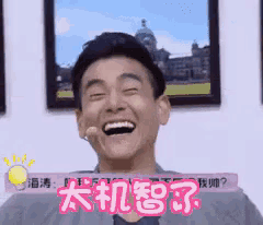 a man is laughing in front of a wall with chinese writing on it .