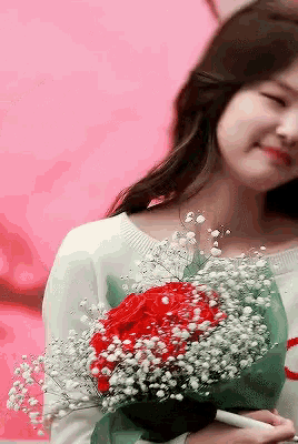 a woman holding a bouquet of red roses and white baby 's breath