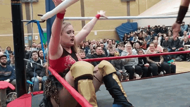 a woman is in a wrestling ring with a crowd watching and a sign that says leplus on it