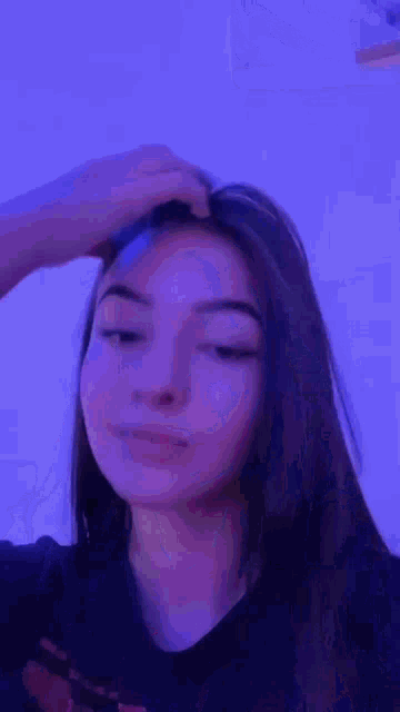 a close up of a woman 's face with a blue background and purple hair .
