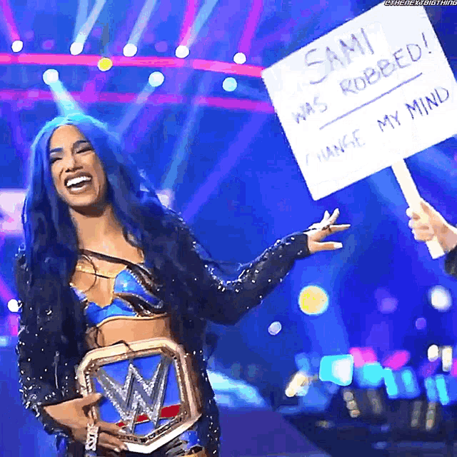 a woman with blue hair is holding a sign that says sani was robbed change my mind