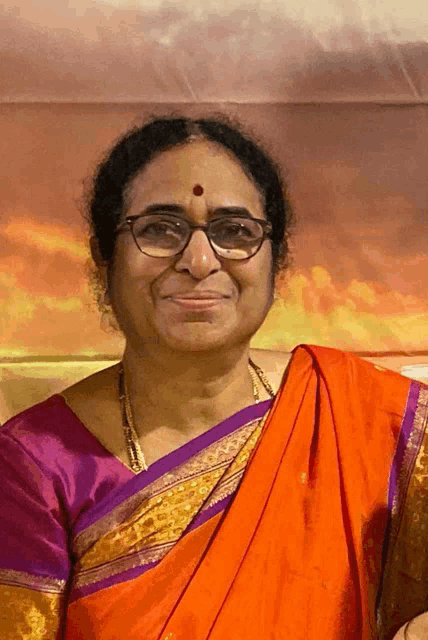a woman wearing glasses and a red dot on her forehead