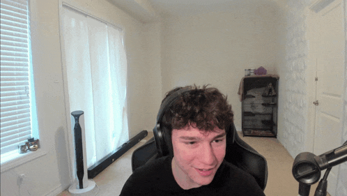 a man wearing headphones sits in front of a microphone in a room