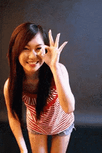 a woman in a red and white striped shirt is giving a ok sign