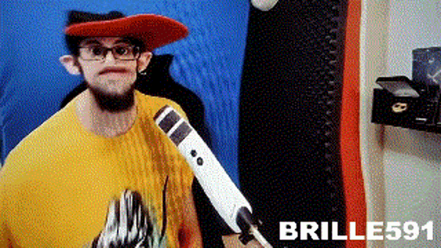 a man wearing a red hat and glasses is holding a microphone in his hand .
