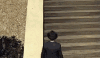 a man in a suit and hat is walking up a set of stairs .
