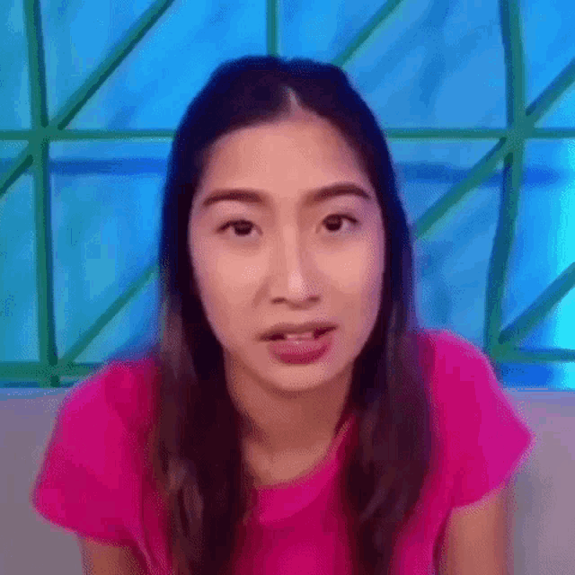a woman in a pink shirt is making a funny face and sticking her tongue out .