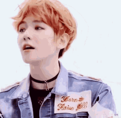 a close up of a person with red hair wearing a denim jacket and a choker .
