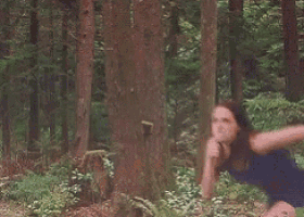 a close up of a person standing in a forest surrounded by trees .