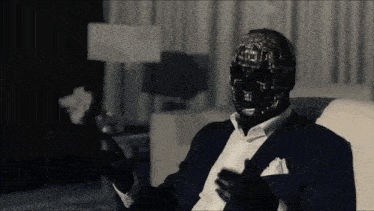 a man in a suit has a black mask on his head