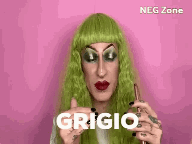 a drag queen with green hair and red lips is holding a cell phone and making a funny face .