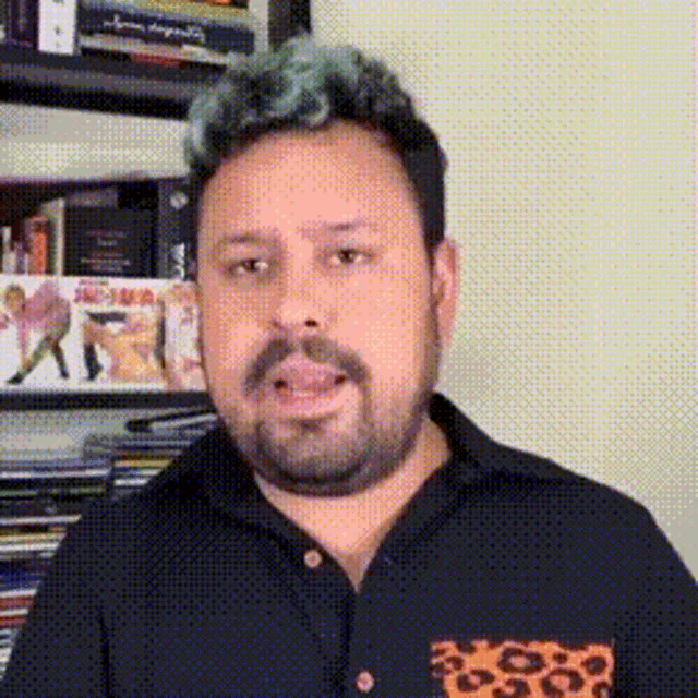a man with a beard and green hair is wearing a black shirt with a leopard print pocket .