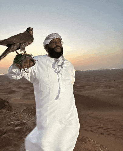 a man in a white robe holds a bird on his shoulder