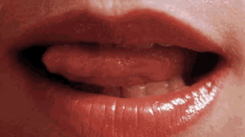 a close up of a woman 's mouth with red lipstick and her tongue sticking out .