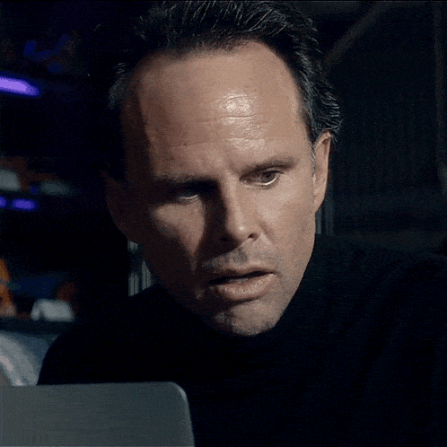 a man in a black turtleneck is looking at a laptop screen