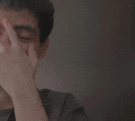 a man is covering his face with his hand while looking down .