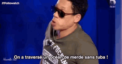 a man wearing sunglasses and a t-shirt that says ' on a traverse un ocean de merde sans tuba '