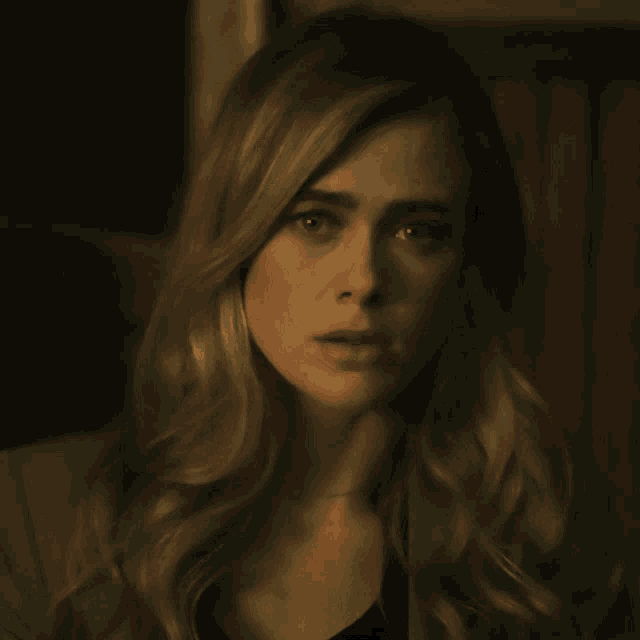 a woman with long blonde hair looks at the camera with a serious look on her face