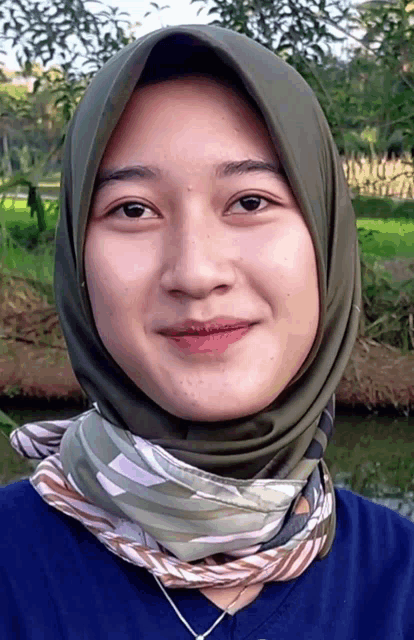 a woman wearing a scarf around her neck and a hijab smiles for the camera