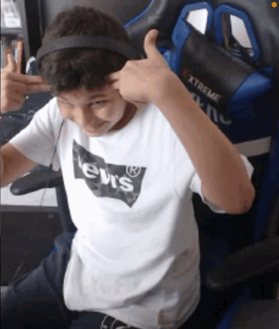 a boy wearing headphones and a shirt that says levis is giving a thumbs up