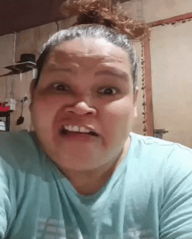 a woman with a bun on her head is making a funny face while wearing a blue shirt .