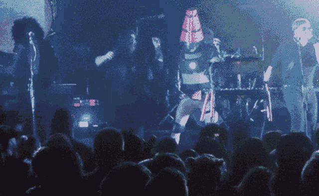 a crowd of people watching a concert with a man in a red cone hat on stage