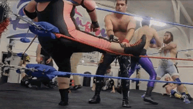 a group of men are wrestling in a ring with a sign that says " wake up " in the back