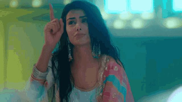 a woman is pointing up with her finger while wearing a colorful dress .