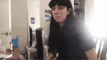 a woman with long black hair looks at the camera