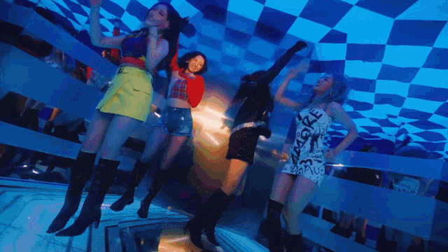 a group of young women are dancing in a room with a checkered ceiling