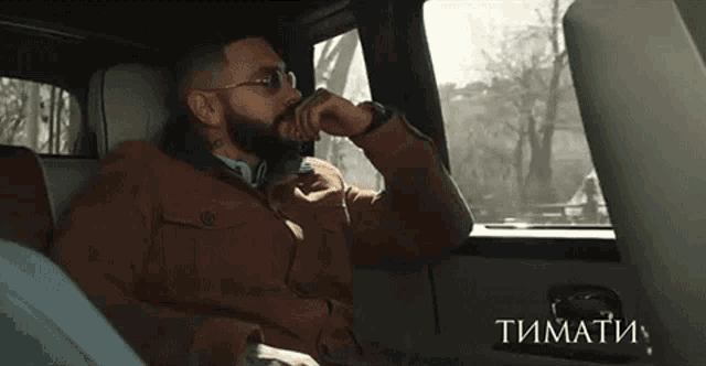 a man wearing sunglasses is sitting in the back seat of a car .