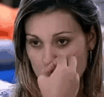 a close up of a woman holding her nose with her hand .