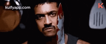 a man is holding a bloody knife in his hand .