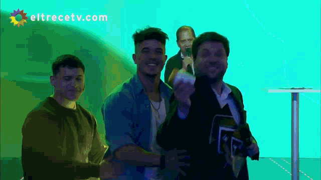 a group of men standing in front of a green background with eltrecetv.com written on the bottom