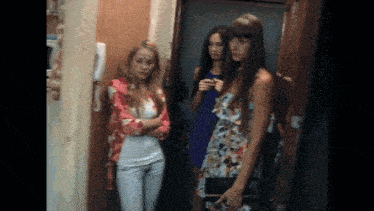 three women are standing next to each other in a room