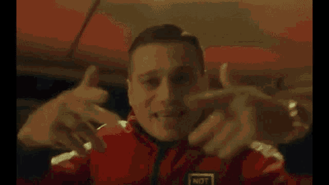 a man in a red and white jacket is dancing in a dark room .