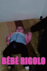 a baby laying on a bed with the words bebe rigolo written in pink