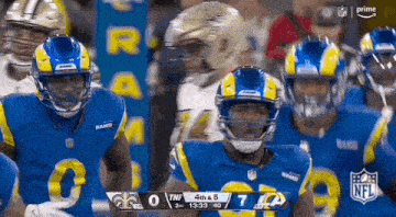 a group of football players are standing next to each other on the field during a game .