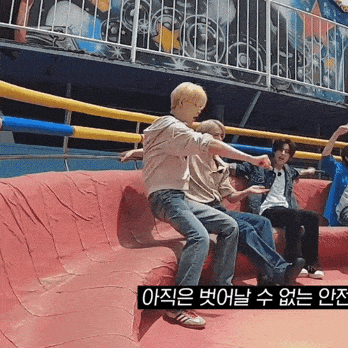 a group of people are sitting on a red couch in front of a roller coaster in korean