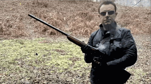 a man is holding a shotgun in a field