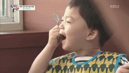 a little boy is holding a fork in his mouth while wearing a bib .