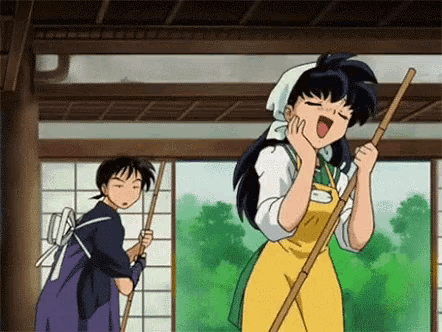 a woman in an apron is holding a broom and yawning while a man stands behind her .