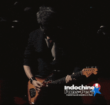 a man playing drums in front of a sign that says indochine fame-peru