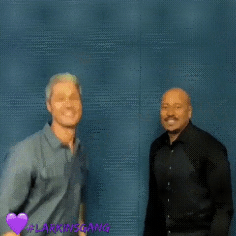 a couple of men are dancing in front of a blue wall .