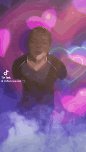 a man is holding a sparkler in his hand in front of a pink and purple background with hearts .
