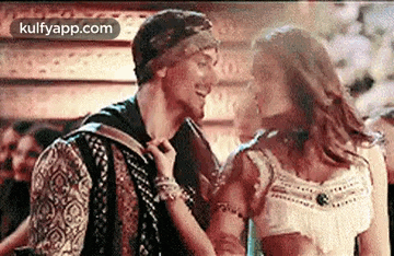 a man and a woman are dancing together in a room . the woman is wearing a white top .