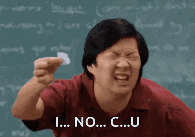 a man is holding a piece of paper and making a funny face in front of a chalkboard .