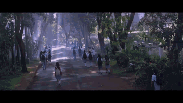 a group of people are walking down a road with trees in the background